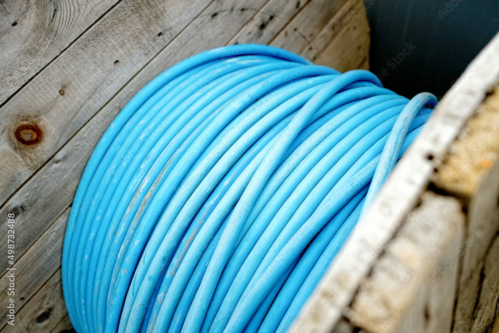 New blue power cable is wound on wooden coil. Background. Cable for laying underground. New blue power cable is wound on wooden coil. Background. Cable for laying underground.