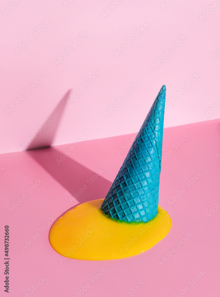 An overturned waffle cone with melted ice cream on a pink background