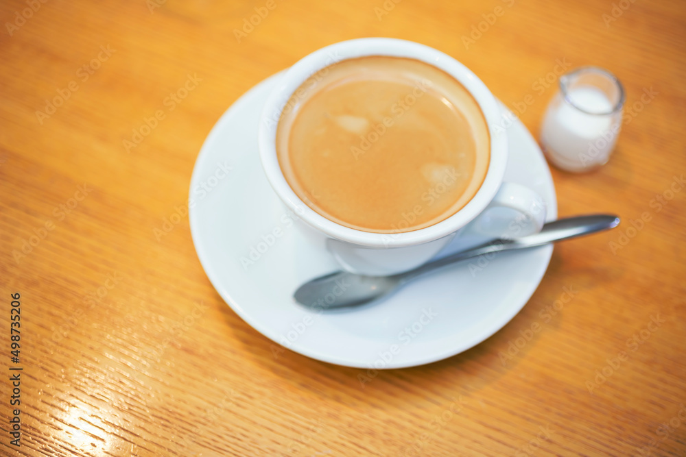木製のテーブルの上のコーヒーとミルクピッチャー 木製のテーブルの上のコーヒーとミルクピッチャー