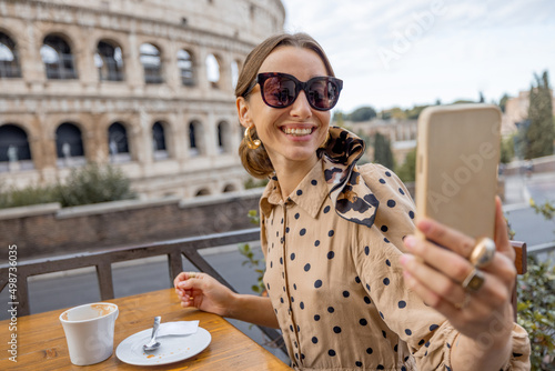 Canvas Print Woman having fun taking selfie with coffee at outdoor cafe on background of coliseum, the most famous landmark in Rome