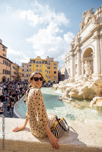 Woman visiting famous di Trevi fountain in Rome. Traveling Italy on a summer day concept. Portrait of caucasian woman in dress and shawl in hair