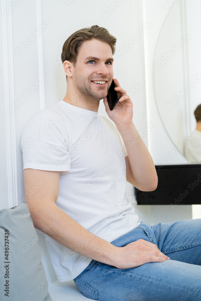 smiling man looking away while sitting on couch and talking on mobile phone. smiling man looking away while sitting on couch and talking on mobile phone.
