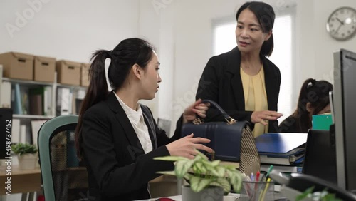 asian woman employee saying no to boss’s request for more jobs and getting off work in a hurry. upset female manager holding piles of paperwork and shaking head