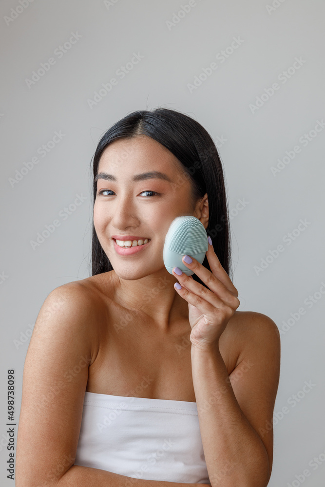 Joyful young woman using face massager in studio Joyful young woman using face massager in studio