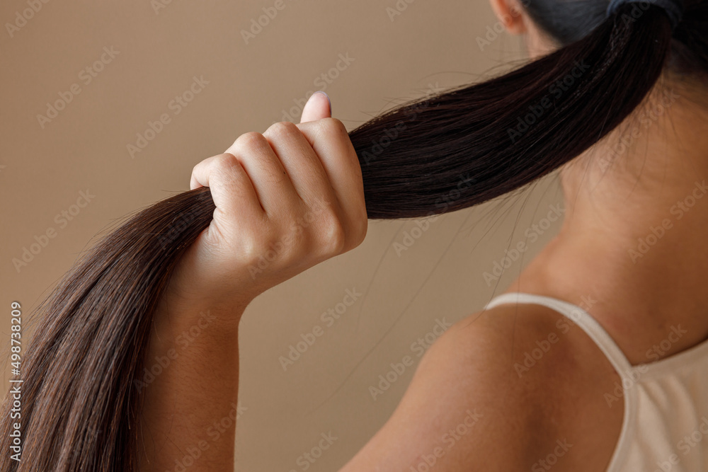Young woman hand holding ponytail in studio - obrazy, fototapety, plakaty 
