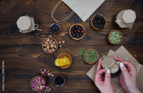 Women's hands tie a jar of collected tea with a string