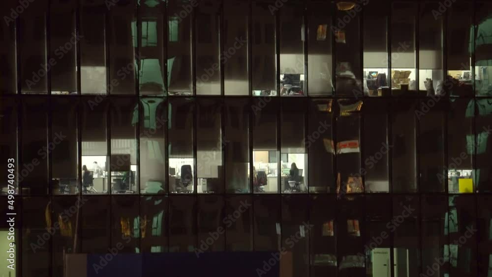 View Through Glass Windows Of Urban Building In Bangkok With Employees Working Overtime Late At Night. - Static View Through Glass Windows Of Urban Building In Bangkok With Employees Working Overtime Late At Night. - Static