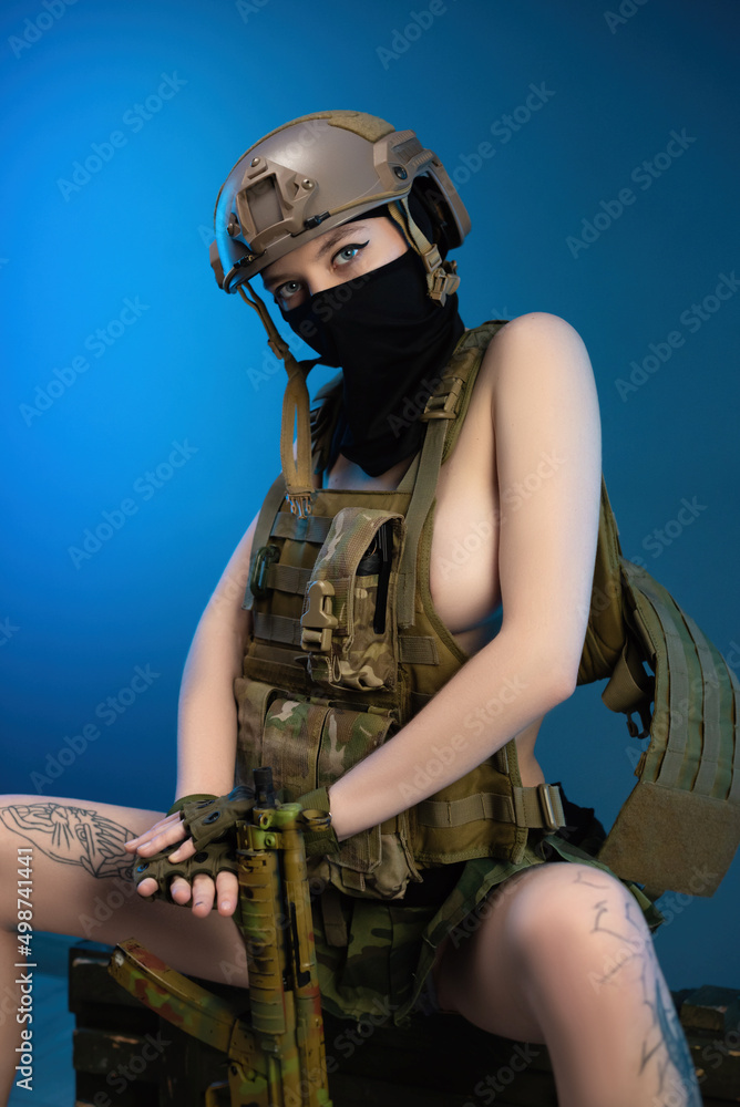 sexy girl soldier in a helmet, armed with an automatic rifle, in military  clothes on a blue background Stock Photo | Adobe Stock