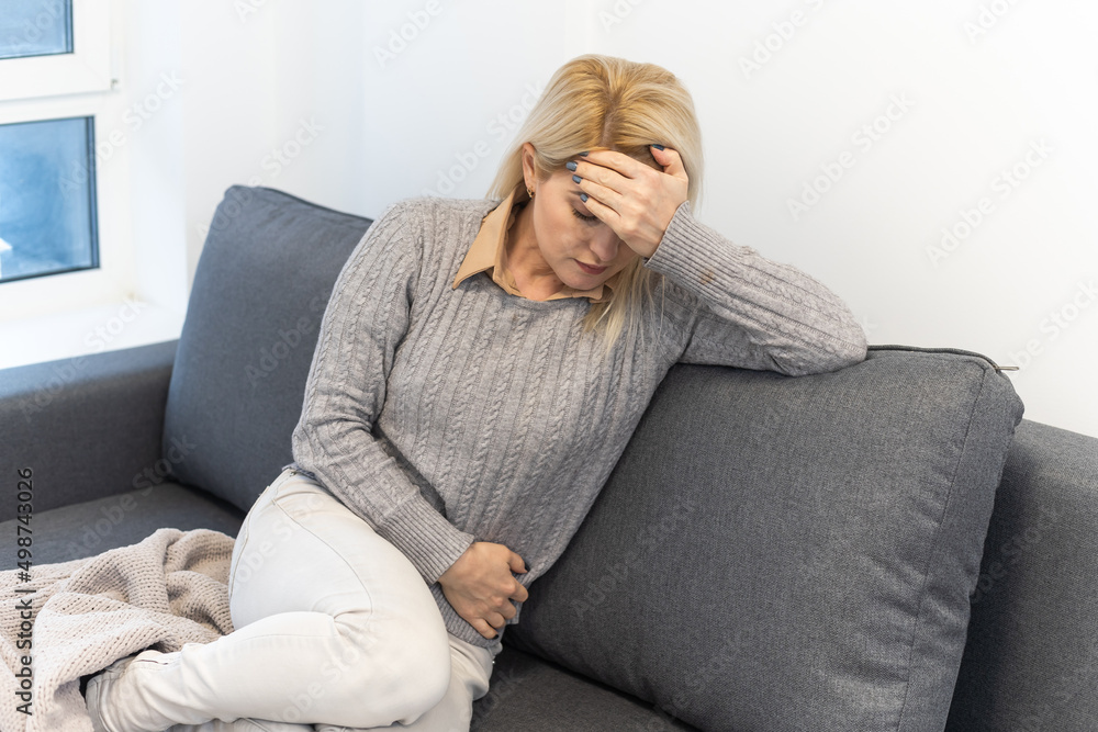 woman lying in bed suffering from stomach pain woman lying in bed suffering from stomach pain