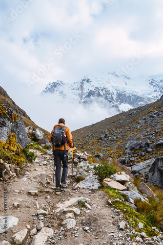 Back view of a caucasian man going uphill to the peak in a snowy mountain landscape.