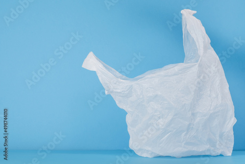 Disposable white plastic bag on a blue background. Space for your text. Plastic free concept.