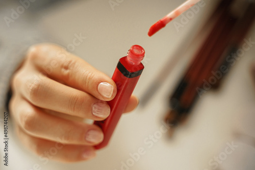 Female hands with tube of red lipstick
