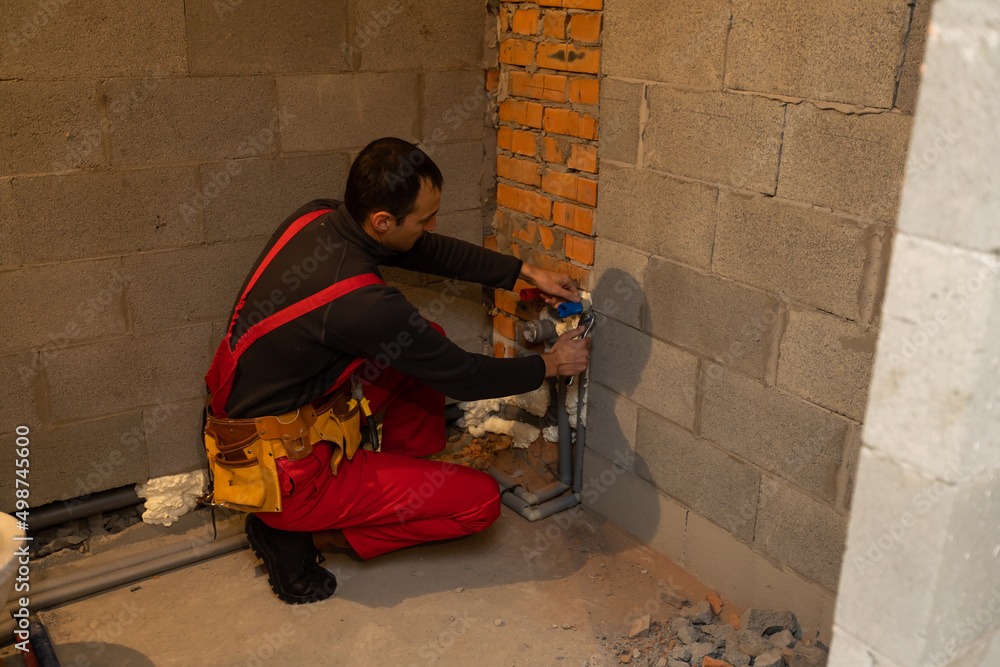 Fototapeta premium building, profession and people concept - builder or plumber working with water pipes in boiler room