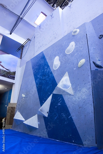 Bouldering climbing problem slab route made on a grey and blue wall with white holds. Ledges, bulges, slopers and crimps photo