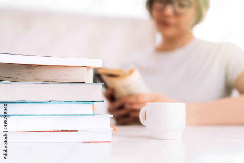 Girl with glasses reading book at table with cup of coffee. Girl with glasses reading book at table with cup of coffee.