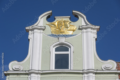 Golden sailing ship on the gable of a merchant house in the historic old town of the hanseatic city of Lubeck in Germany, blue sky, copy space
