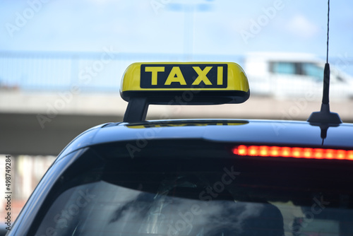 Yellow taxi sign on a black car in the city, detail of the vehicle for hire, copy space, selected focus