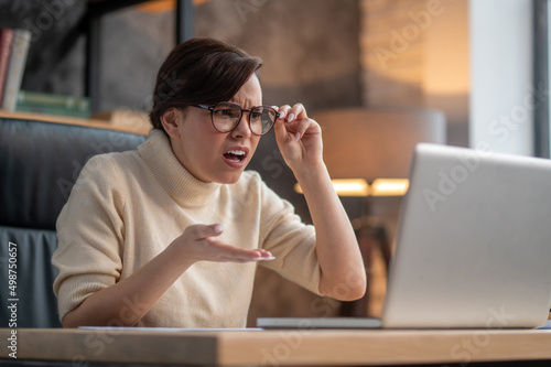 фотографія A woman in eyeglasses looking surprised and uncertain