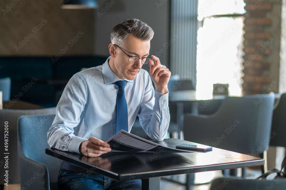 Mid aged man in elegant clothes sitting at the table in a cafe Mid aged man in elegant clothes sitting at the table in a cafe
