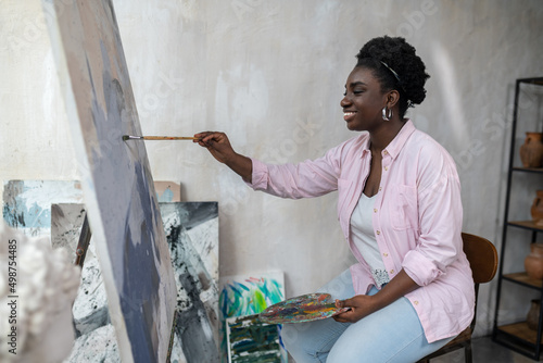 Foto A dark-skinned woman sitting near the easel and painting