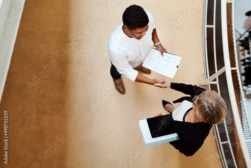 Coming together to excel together. High angle shot of two businesspeople shaking hands in an office. photo