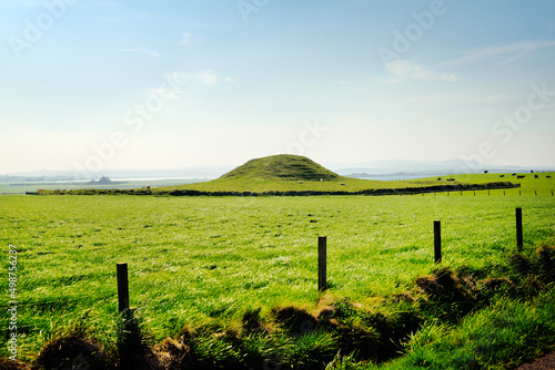 Maes Howe Neolithic chambered cairn passage grave. Mainland, Orkney, Scotland. 5000 years old. Stenness (L) and Brodgar (R) stones in distance photo