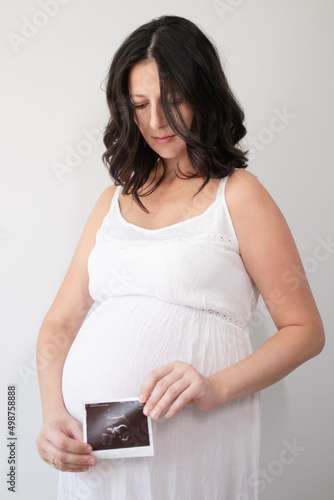 pregnant woman with a photo of ultrasound of pregnancy. enjoying pregnancy happy time. mother to be with cute big tummy