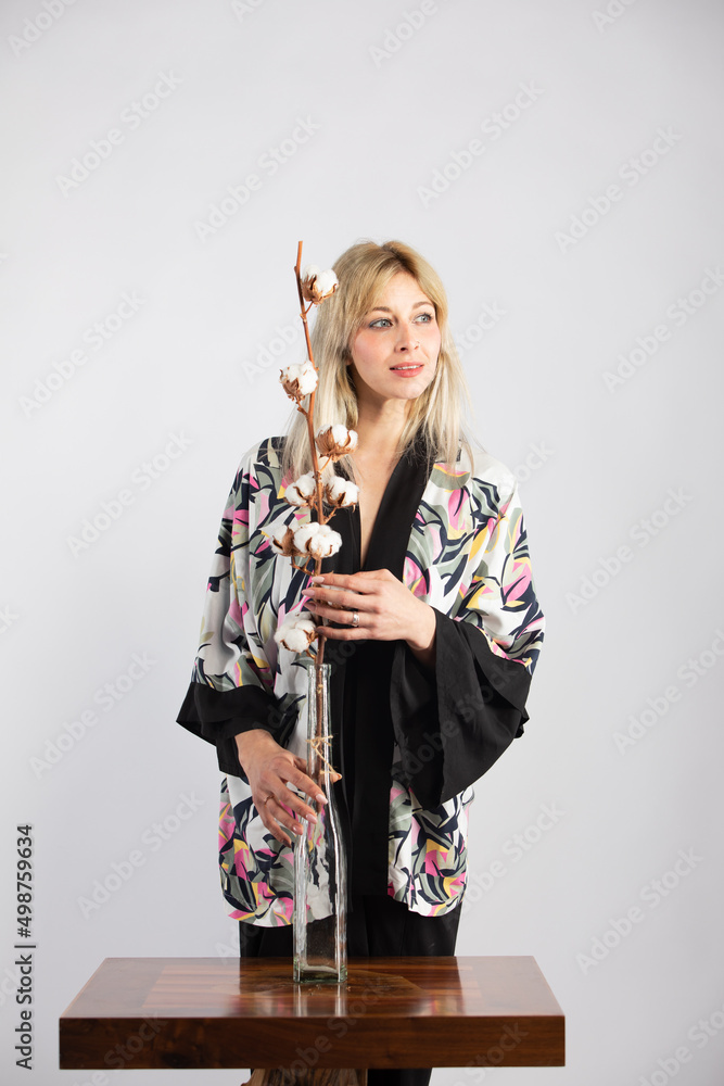 Attractive blonde woman in a black trendy and fashionable colorful kimono in a white background Attractive blonde woman in a black trendy and fashionable colorful kimono in a white background