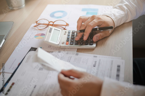 Close up hand of stress young asian businessman,male is pressing a calculator to calculate tax income and expenses, bills, credit card for payment or payday at home, office.Financial, finance concept.
