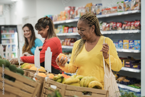 фотографія African senior woman buying fresh organic fruits at supermarket