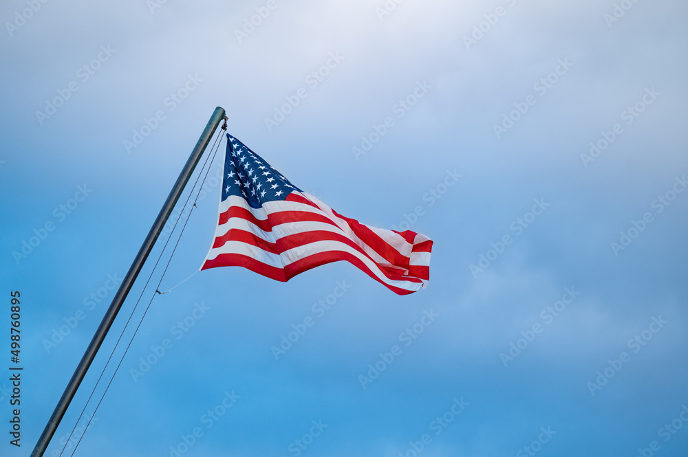 sunlit american flag against a gray sky sunlit american flag against a gray sky