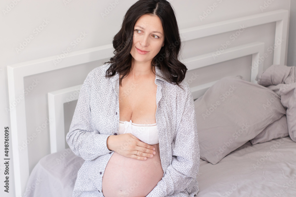 charming pregnant woman in shirt on bed. happy pregnancy charming pregnant woman in shirt on bed. happy pregnancy