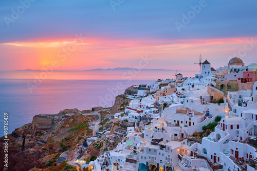 Famous greek iconic selfie spot tourist destination Oia village with traditional white houses and windmills in Santorini island on sunset in twilight, Greece © Dmitry Rukhlenko