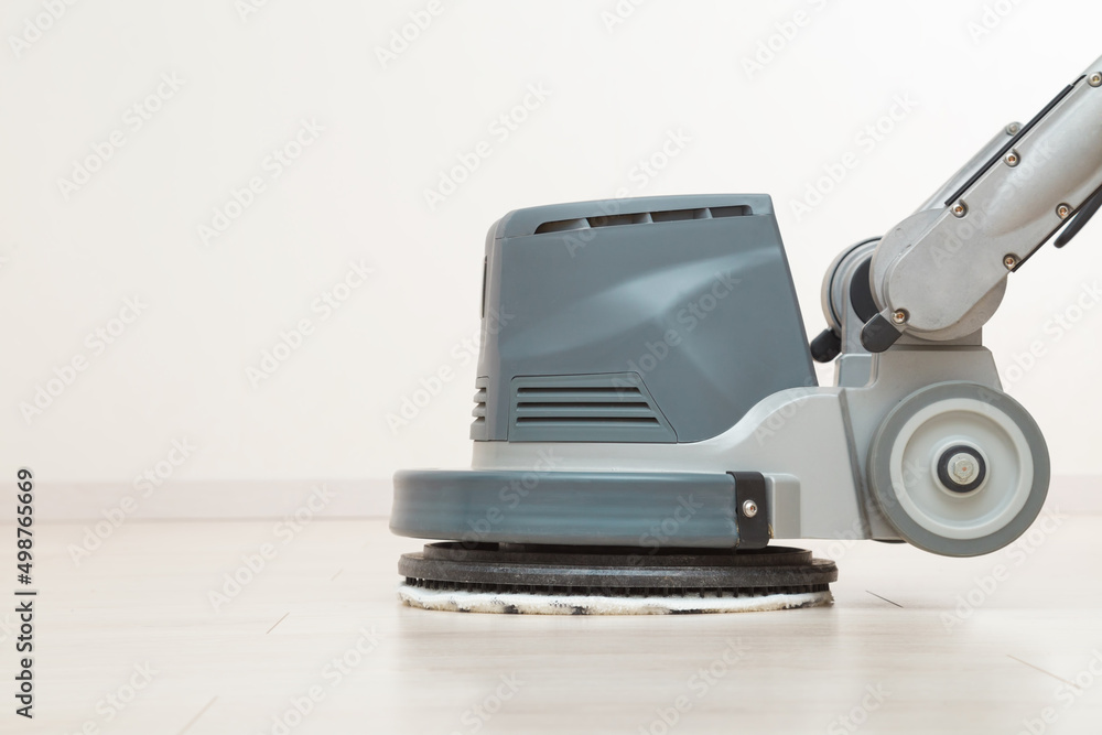 Professional disc machine with microfiber soft pad polishing and waxing light laminate floor surface at home room. Closeup. Commercial service. Side view. Professional disc machine with microfiber soft pad polishing and waxing light laminate floor surface at home room. Closeup. Commercial service. Side view.