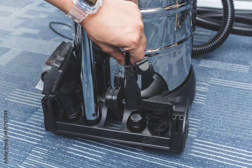 Storing vacuum cleaner attachments on a tray at the back of a chrome upright vacuum device. photo