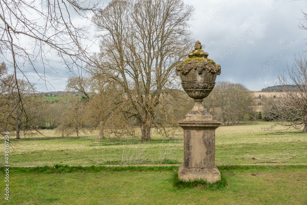 Obraz premium stone statue overlooking parkland in the english countryside