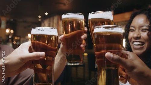 Multi-ethnic group of friends clinking glasses of beer at a restaurant.