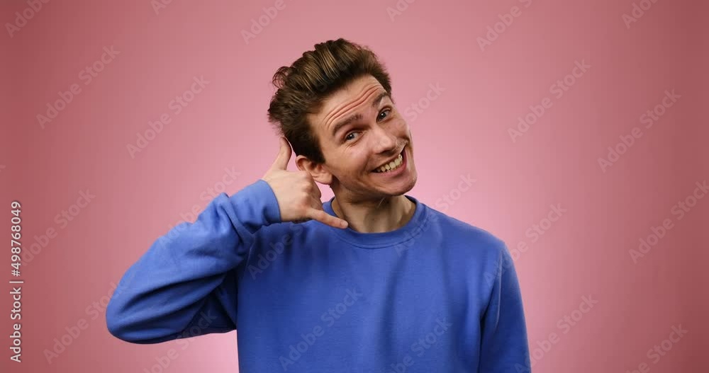 Man showing call me gesture over pink background