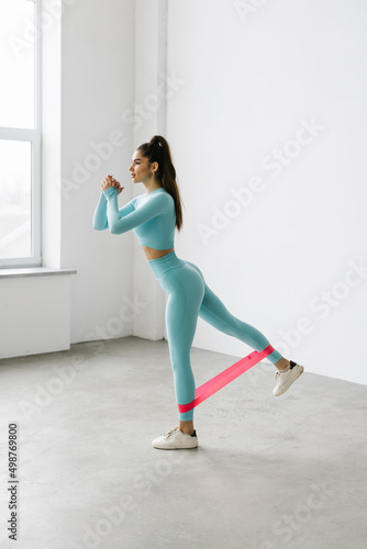 Fitness woman exercising fitness resistance bands on mattress on white background