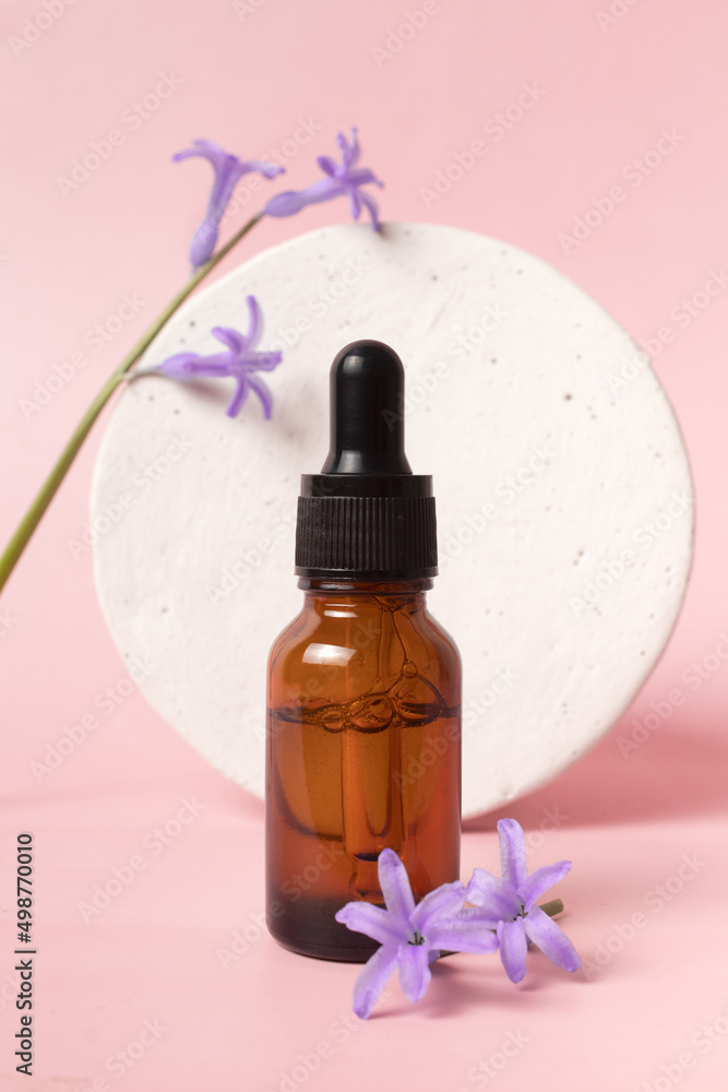 Serum glass bottle with pipette and beautiful flower on pink background. Natural Organic Spa Cosmetic concept. Front view. Serum glass bottle with pipette and beautiful flower on pink background. Natural Organic Spa Cosmetic concept. Front view.
