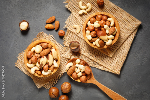 Various nuts in bowl - cashew, hazelnuts, almonds, brazilian nuts and macadamia on a gray stone background. Top view.