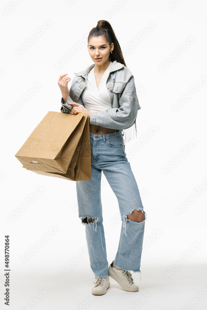 Portrait of young happy smiling woman in jeans jacket with shopping bags, isolated over white background Portrait of young happy smiling woman in jeans jacket with shopping bags, isolated over white background