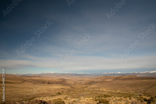View of the golden valley and meadow under a deep blue sky. The Andes mountain range in the background.