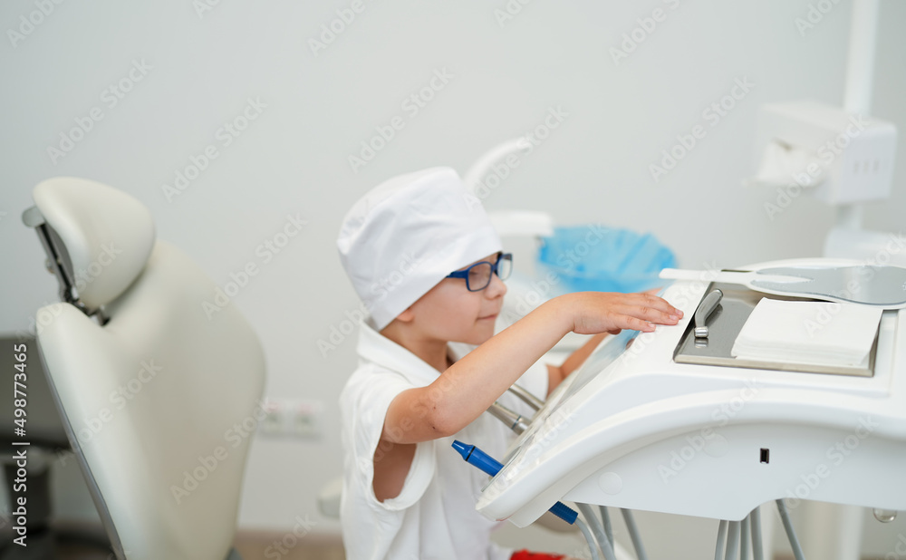 Little boy in white doctor coat playing in dentist. Kid playing with dentistry equipment. Little boy in white doctor coat playing in dentist. Kid playing with dentistry equipment.