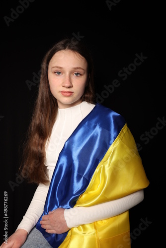 beautiful girl with the flag of Ukraine on a black background. war in Ukraine. patriot of his state. children of war. yellow and blue flag
