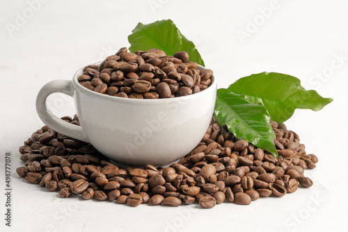 Coffee bean medium roasted in cup with leaf in fresh morning isolated on white background.