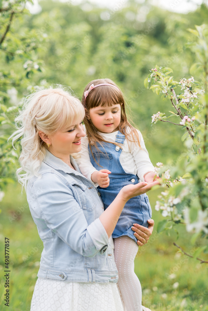 Portrait of a mother with a little daughter in a blooming spring garden