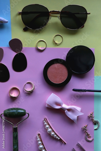 Various accessories, make up products and jewelry on various colorful pastel backgrounds. Flat lay.