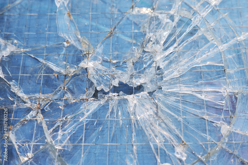 The background is a blue-tinted texture of broken glass with selective focus. The glass with metal bars cracked.