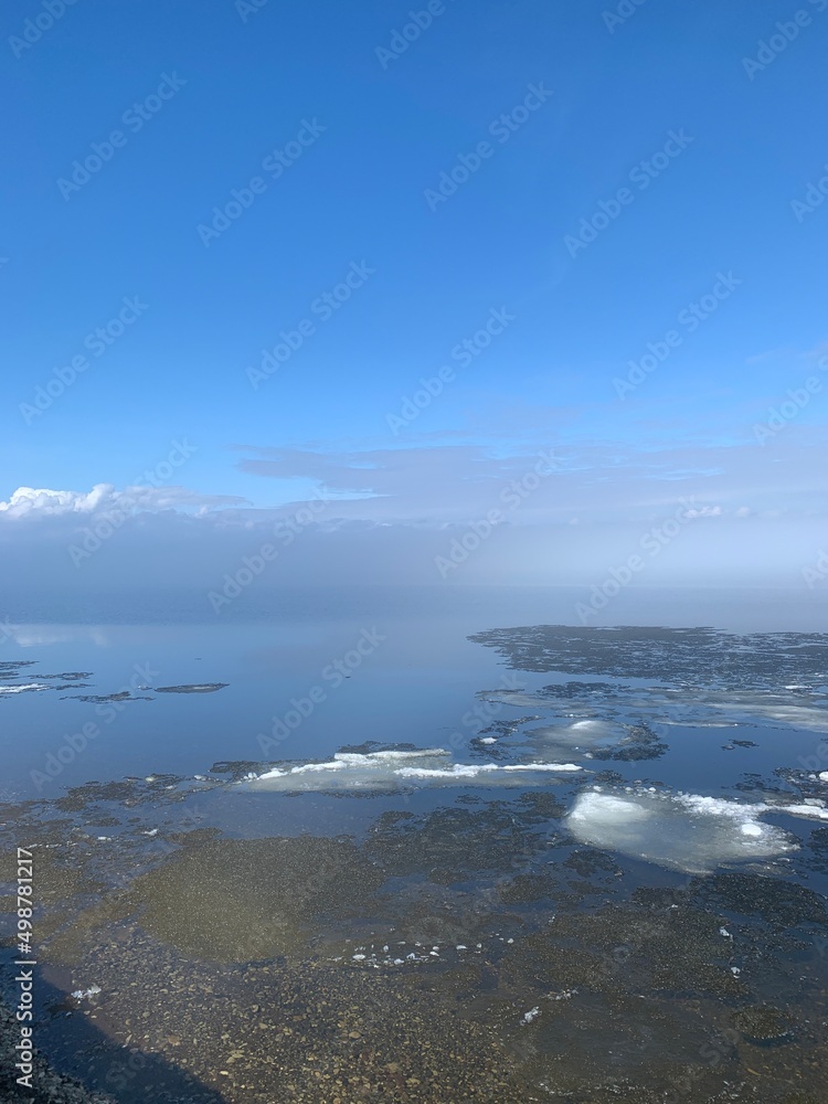 Volga river in April: snow melting, ice drift and high water. Fog and blue sky reflected in the water